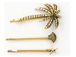 Detailed close-up of gold metal hair clips set with coconut tree, shell, and starfish charms