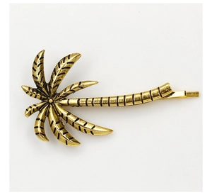 Close-up of coconut tree hair clip with retro gold finish and etched metal textures