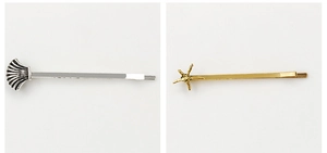 Detail of silver scallop and gold starfish metal hair clips with fine nautical texture