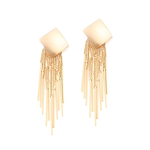 Detail of long gold tassel earrings featuring a square stud and polished metal fringe