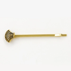 Vintage gold metal hair clip with detailed seashell charm on a minimalist bobby pin