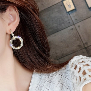 Detalle de elegantes pendientes de aro dorados con strass brillantes usados por una modelo