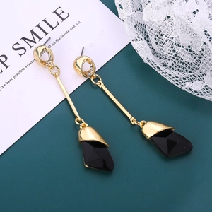 Detail of elegant gold drop earrings with black geometric pendant and sparkling crystals
