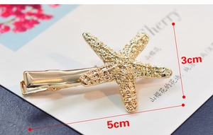 Détail d'une pince à cheveux étoile de mer dorée texturée mesurant environ 5cm sur 3cm