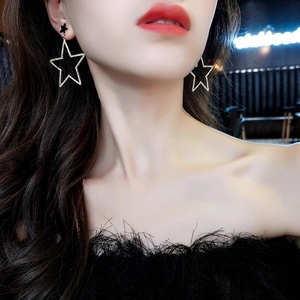 Gros plan de grandes boucles d'oreilles étoiles avec strass scintillants et clou étoile noir