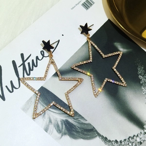 Détail macro de grandes boucles d'oreilles étoiles dorées avec pavé de cristaux