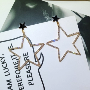 Détail macro de boucles d'oreilles étoiles avec clous noirs et cristaux scintillants