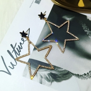 Boucles d'oreilles étoiles dorées chic avec cristaux sur fond de magazine de mode