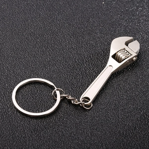 Detailed close-up of a silver mini adjustable wrench keychain on a black textured surface