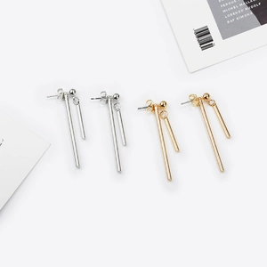 Détail de boucles d'oreilles asymétriques en barres dorées et argentées sur fond blanc