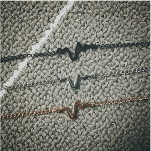 Detailed view of ECG heart rate charms in matte black, silver, and rose gold finishes