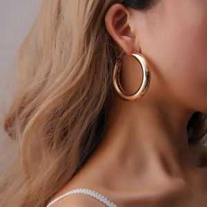 Detailaufnahme goldener Chunky-Creolen mit poliertem Metall-Finish an einem Model