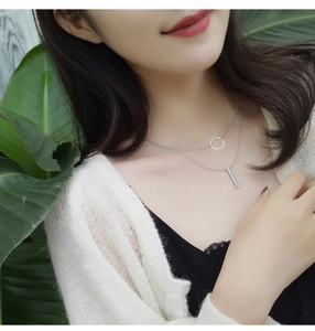 Close-up of minimalist layered necklace with silver ring and vertical bar pendants