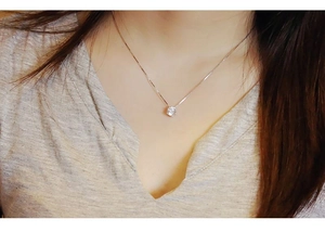 Detail of a minimalist six-prong solitaire zircon necklace on a rose gold chain