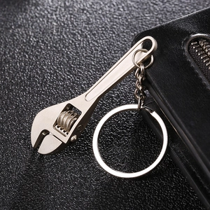 Mini metal adjustable wrench keychain with matte finish on black leather background