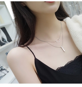 Close-up of double-layer silver necklace with geometric circle and vertical bar pendants