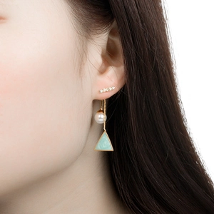 Elegant gold drop earrings with diamonds, pearls and green triangle charms on a model