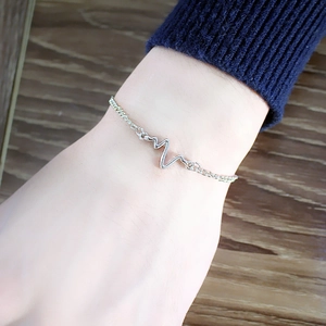 Minimalist silver heartbeat pulse chain bracelet shown on woman's wrist with cozy knit background