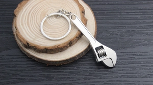 Detail of creative mini adjustable metal wrench keychain on a light wood background