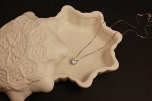 Detailed view of a six-claw zircon pendant necklace on a decorative ceramic jewelry tray