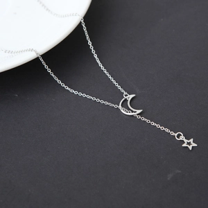 Collier minimaliste argenté avec pendentif lune et étoile sur fond contrasté noir et blanc