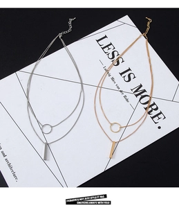 Detail of minimalist double-layer necklace with gold ring and vertical bar pendants