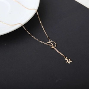 Détail macro de charmes lune et étoile dorés sur un collier à chaîne à maillons fins