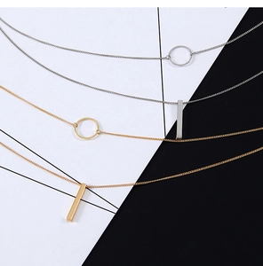Detailed view of silver and gold geometric circle and vertical bar double-layered necklaces