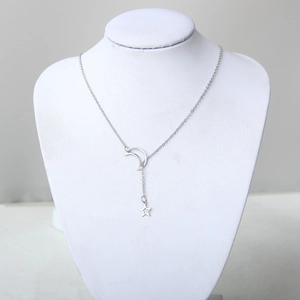 Détail d'un collier en Y argenté avec pendentif croissant de lune et étoile sur buste