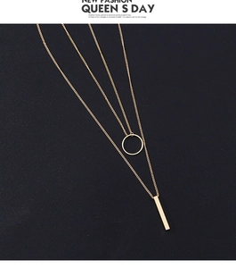 Detailed view of golden double-layer necklace with circular and vertical bar pendants