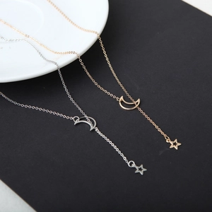 Collier chic en forme de Y or et argent avec lune et étoile sur une assiette minimaliste