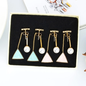 Detail view of geometric enamel earrings with pearls and crystals on black velvet