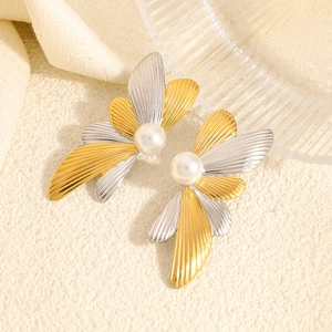 Artistic two-tone floral stainless steel earrings with central pearl on neutral background