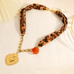 Detail of bohemian gold heart pendant with silk leopard print ribbon and resin bead accent