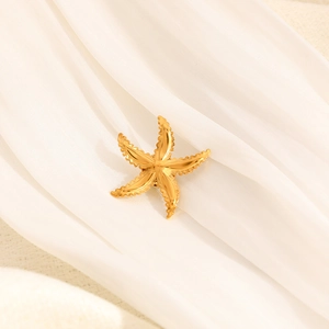 Macro detail of 18k gold plated starfish brooch featuring wavy textures on white silk