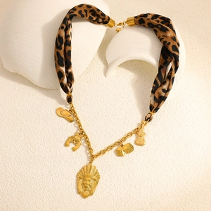 Leopard silk scarf necklace with 18K gold cowboy hat and guitar pendants on ceramic stand