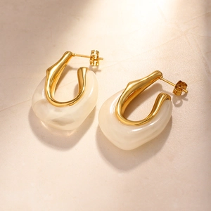 Vintage σκουλαρίκια U-shape 18K χρυσά με κρέμα ρητίνη σε πέτρινο φόντο