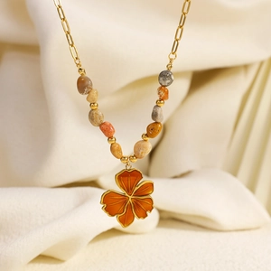 Detailed close-up of an orange enamel flower pendant on a natural stone beaded necklace