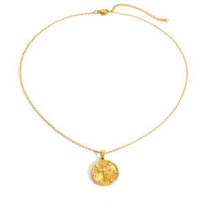 Detailed macro view of gold-plated circular pendant with cross relief and cubic zirconia
