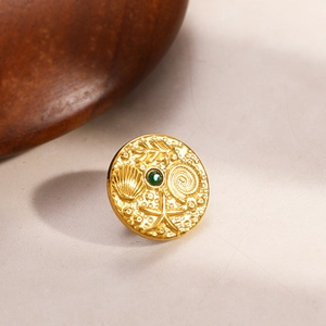 Makroaufnahme einer goldenen Ozean-Brosche mit Seesternmotiven und grünem Edelstein
