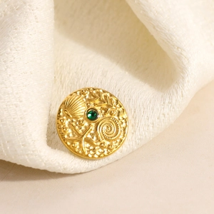 Nahaufnahme einer goldenen Brosche mit grünem Stein und Reliefmotiven aus dem Meer