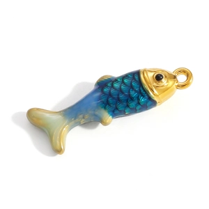Macro detail of blue enamel fish pendant with golden metal scales and boho design