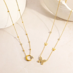 Dettaglio di collane placcate in oro 18K con ciondoli a farfalla e luna con zirconi incastonati