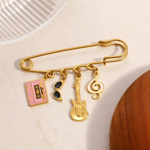 Detail of gold safety pin brooch featuring lover tape, guitar, and music note charms
