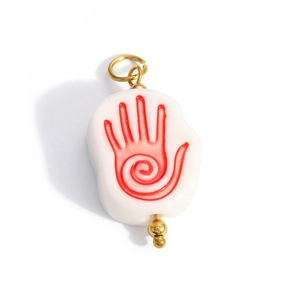 Detailed view of pebble-shaped white charm with red palm print and gold loop hardware