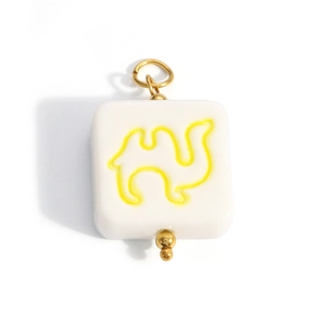 Detailed macro view of square white enamel camel charm with golden metal hanging ring