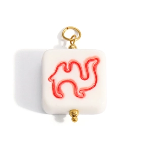 Macro detail of square resin charm with red camel pattern and gold metal ring attachment