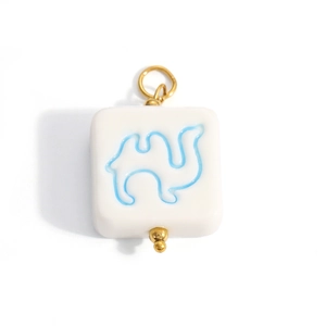 Detailed view of white ceramic square pendant with blue camel print and gold ring hook