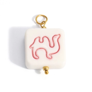 Detail of square white pendant with pink camel motif and gold metal ring attachment