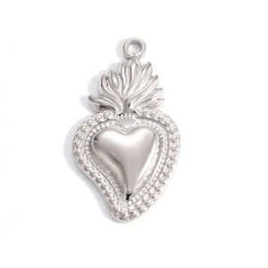Detailed macro view of a silver sacred heart pendant with flame and beaded edge